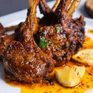 Oven Baked Lamb Chops standing up on a plate.