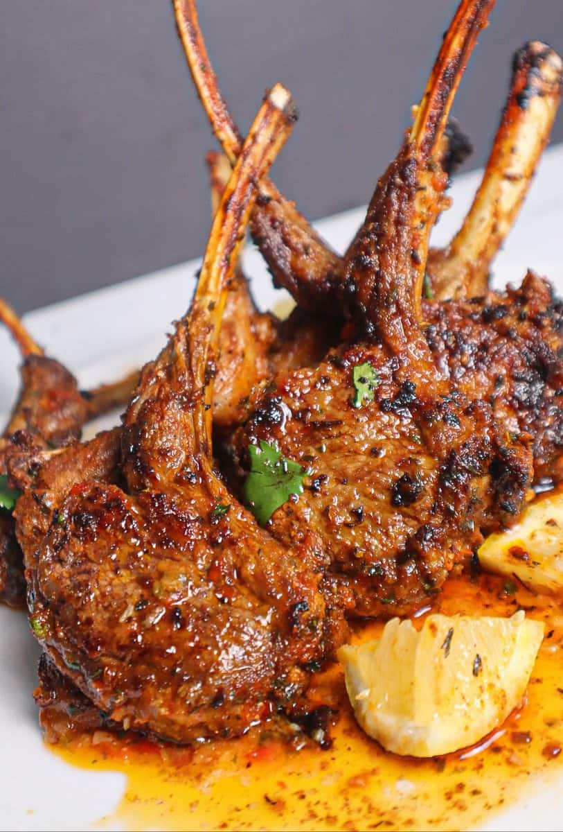 Baked Lamb Chops standing up on a white plate.