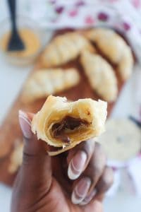 Person holding part of a pulled-apart chocolate croissant.