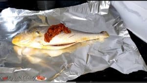 Marinade on a fish set on a sheet of aluminum foil.