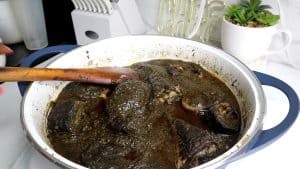 Wooden spoon stirring fish in a pot.