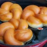 Twisted Donuts frying in hot oil.