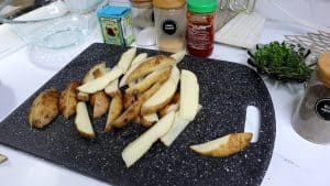 Raw potato wedges on a cutting board.