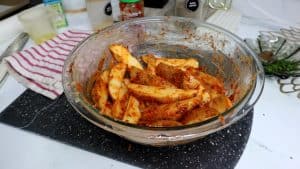 Seasoned potato wedges in a glass bowl.