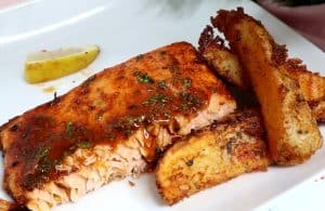 Plate of Baked Firecracker Salmon with potato wedges.