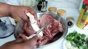 Person cutting slits into the fatty side of pork chops.