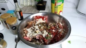 Pork chops marinating in a metal bowl.