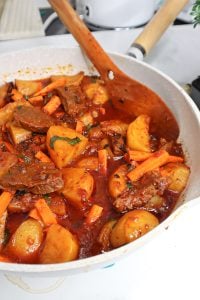 Wooden spoon in a pan of African Stewed Potatoes - Potatoes Hot Pot.