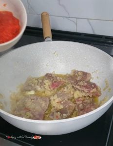 Beef cooking in a pan with onion and garlic.