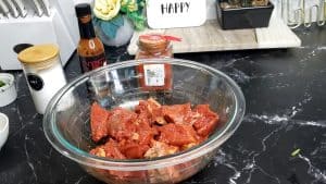 Chunks of beef marinating in a glass bowl.