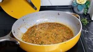 Hot sauce cooking with seasonings in a yellow skillet.