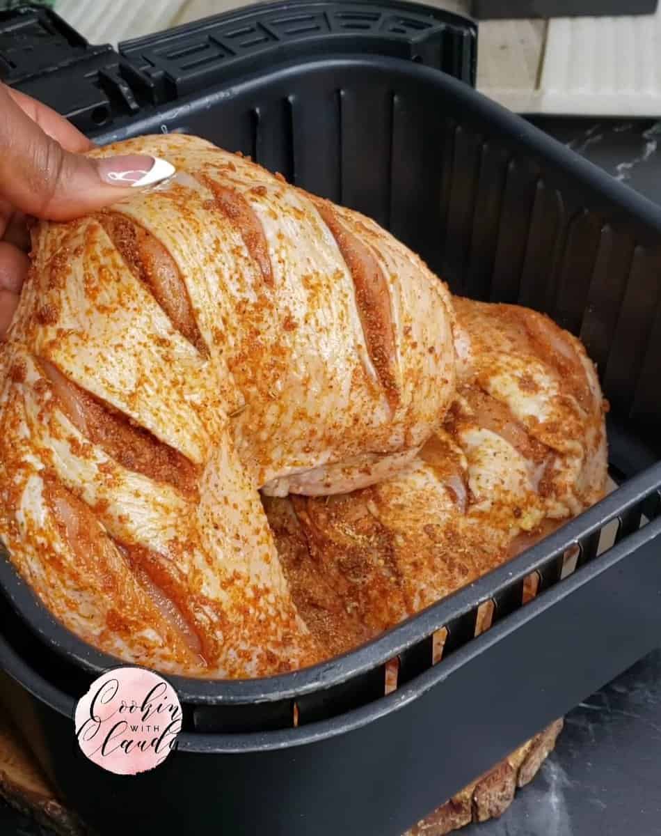Person placing chicken legs into an air fryer basket.