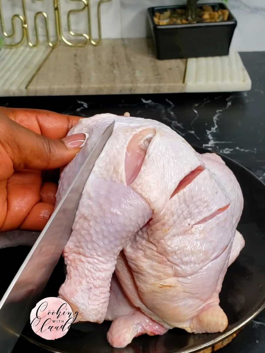 Person cutting slits into a chicken leg.