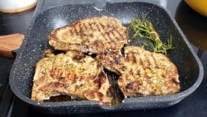 Partially-cooked pork chops in a grill pan.