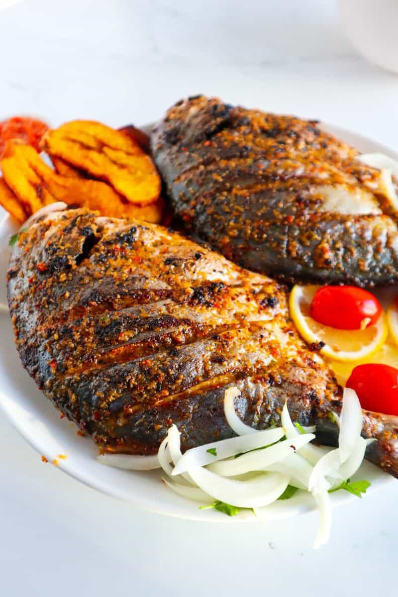 Whole fish on a plate with vegetables.