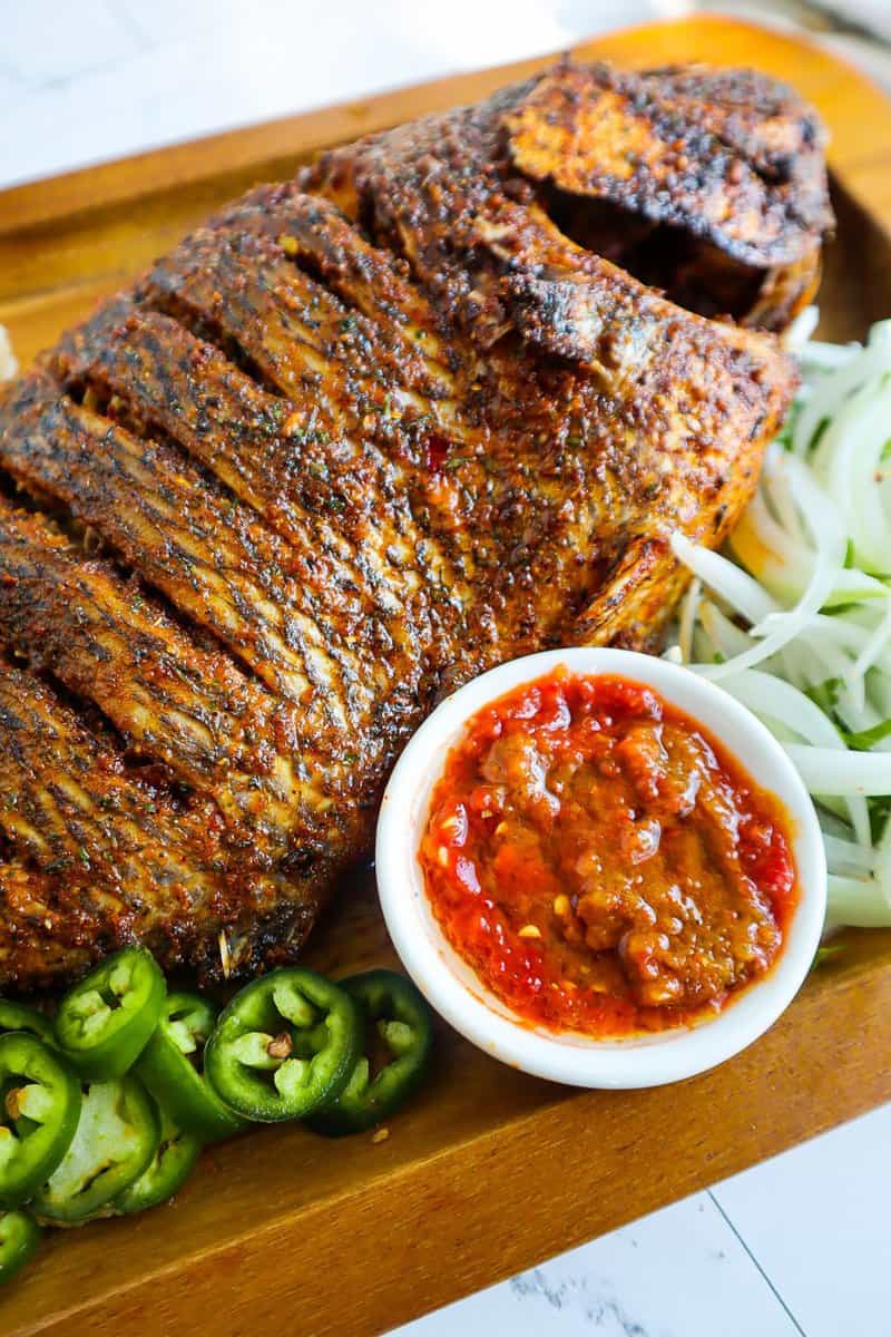 Oven-baked whole tilapia on a wooden board.