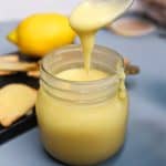 Spoon drizzling lemon curd into a jar.