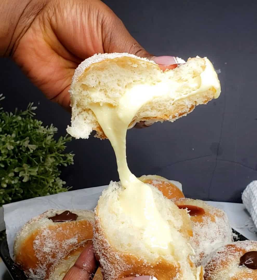 Person holding two halves of a Milk-Filled Donut.