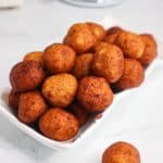 Accra Banana (Banana and Cassava Fritters) piled in a white dish with a paper towel.