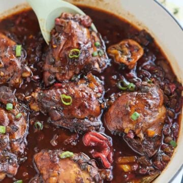 Spoon scooping chicken from a pot of Jamaican Brown Stew Chicken.