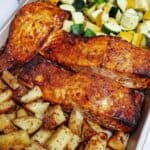 Salmon and Crispy Potatoes and Veggies on a baking sheet.