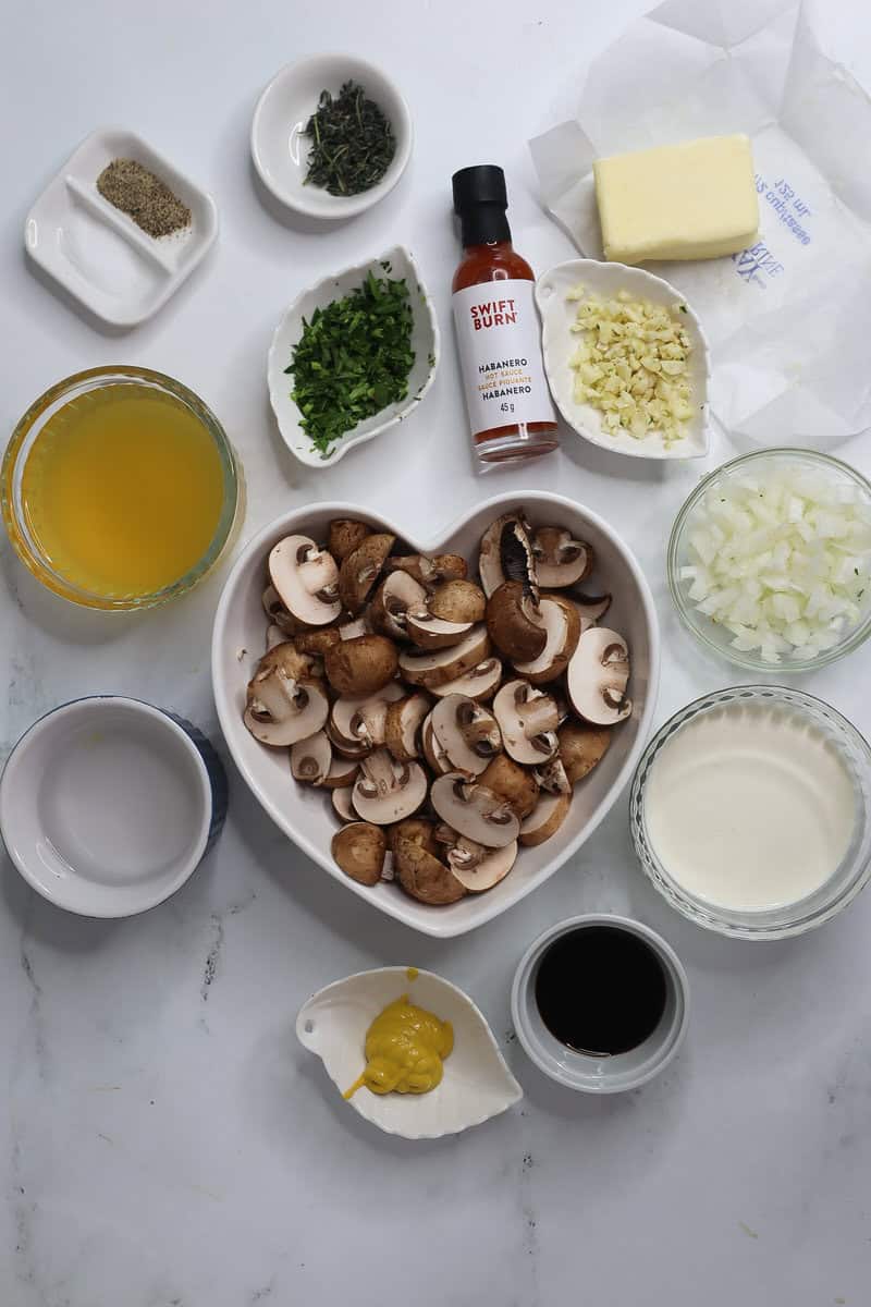 Ingredients for Creamy Mushroom Sauce including cremini mushrooms, hot sauce, and broth.