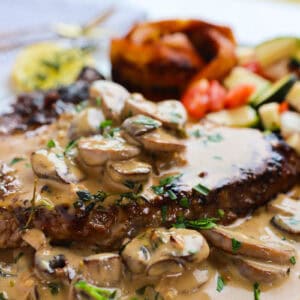 Creamy Mushroom Sauce over a steak on a plate.