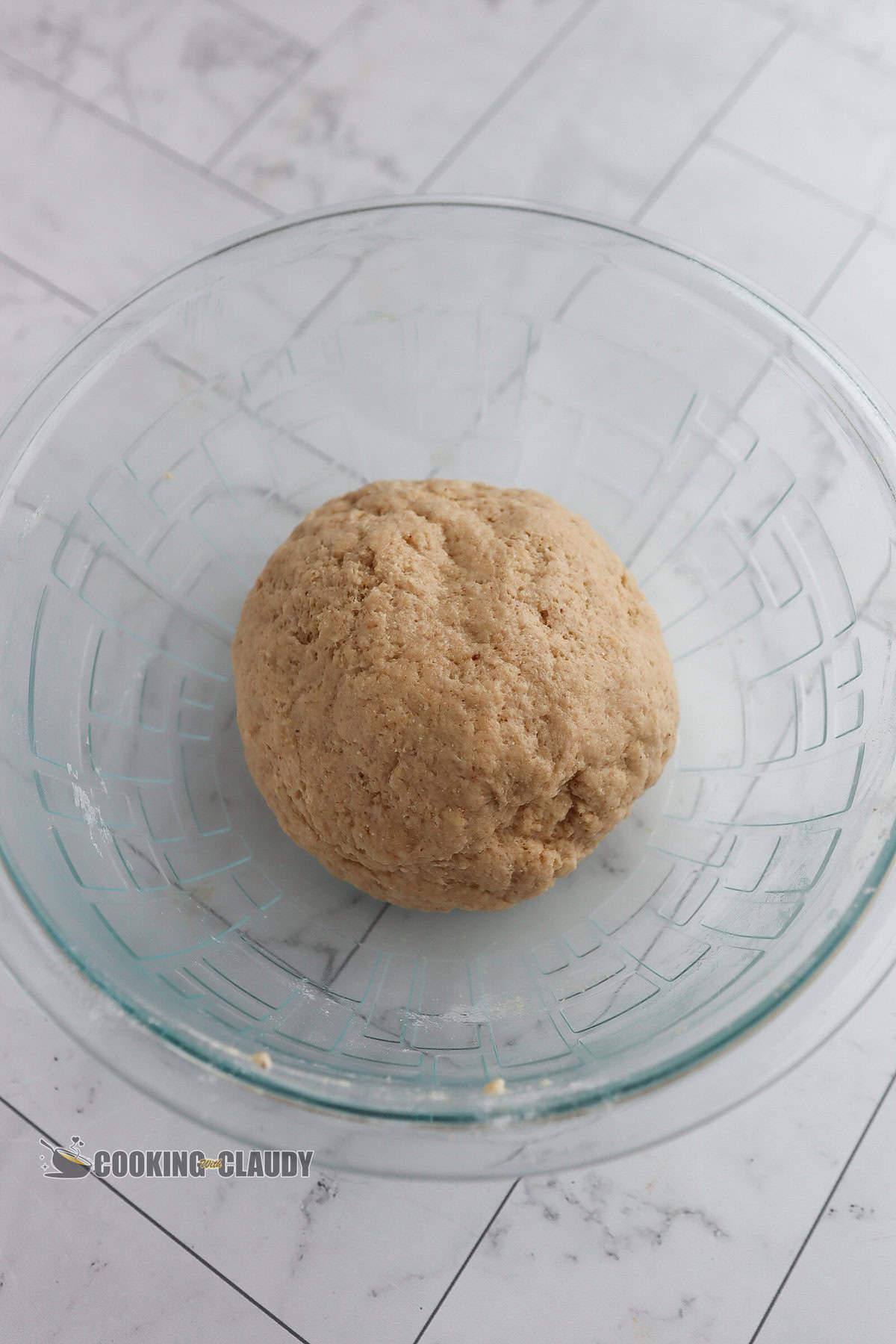 Ball of dough in a glass bowl.