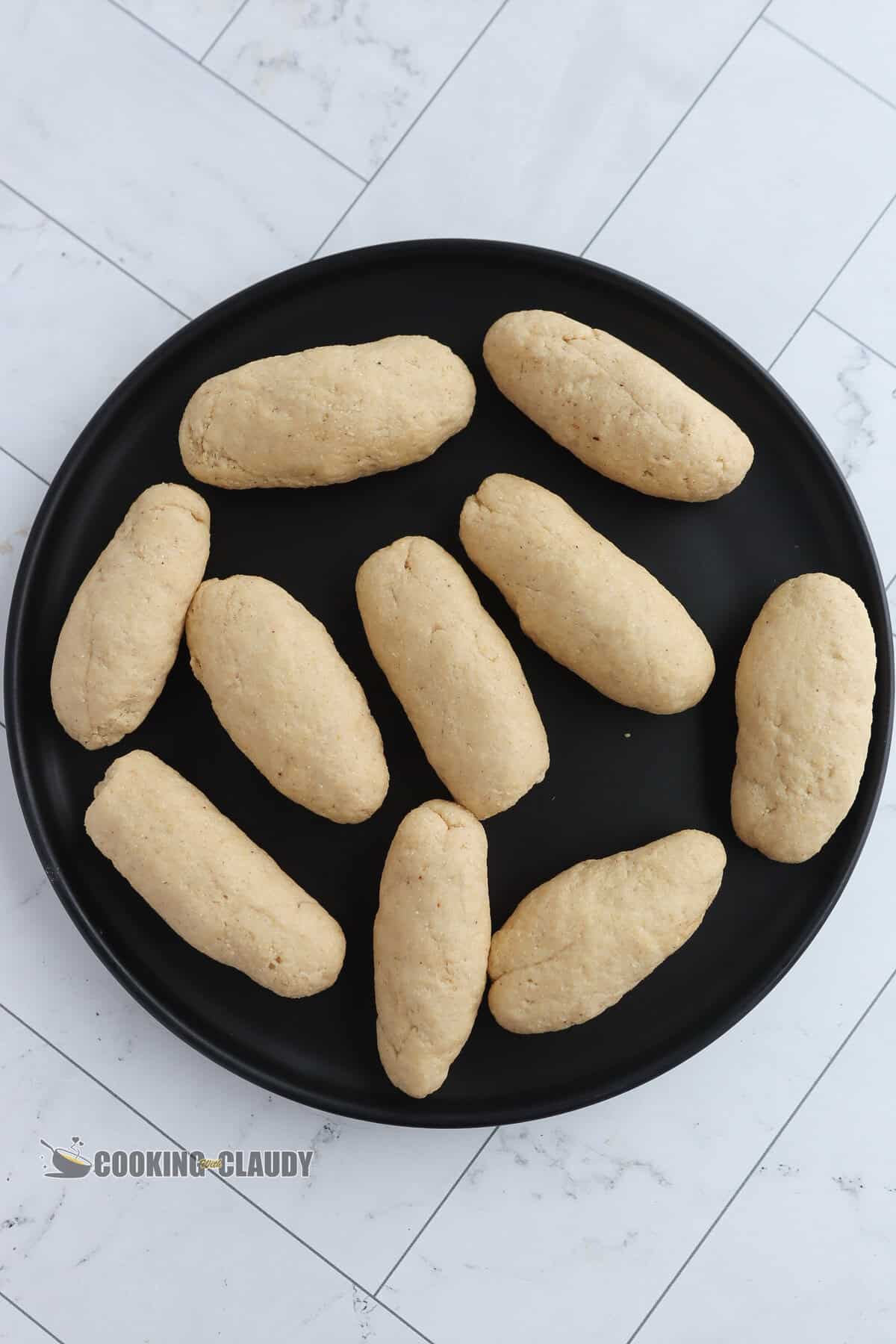 Long, oval rolls of dough on a black plate.