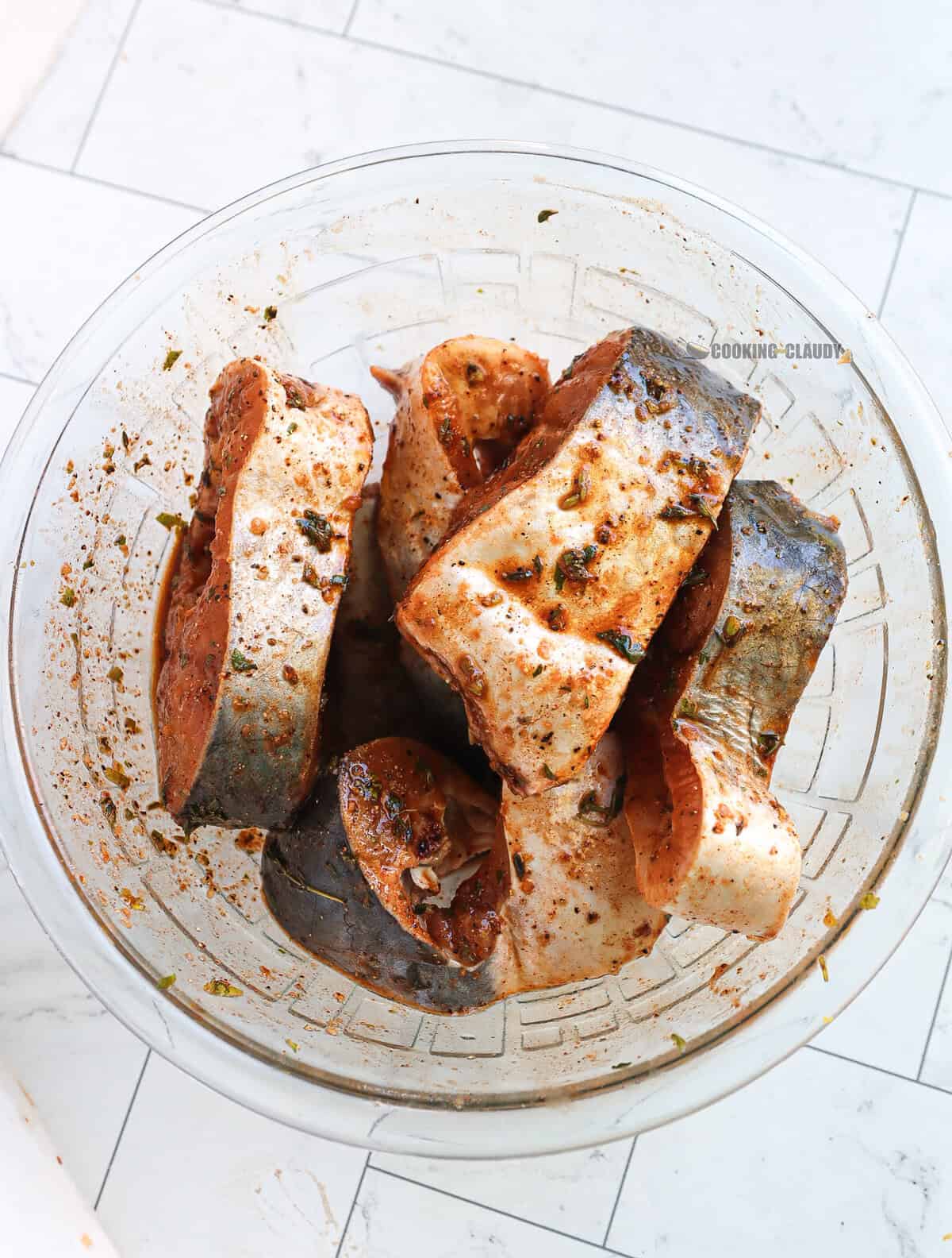 Glass bowl of Basa fish and marinade.