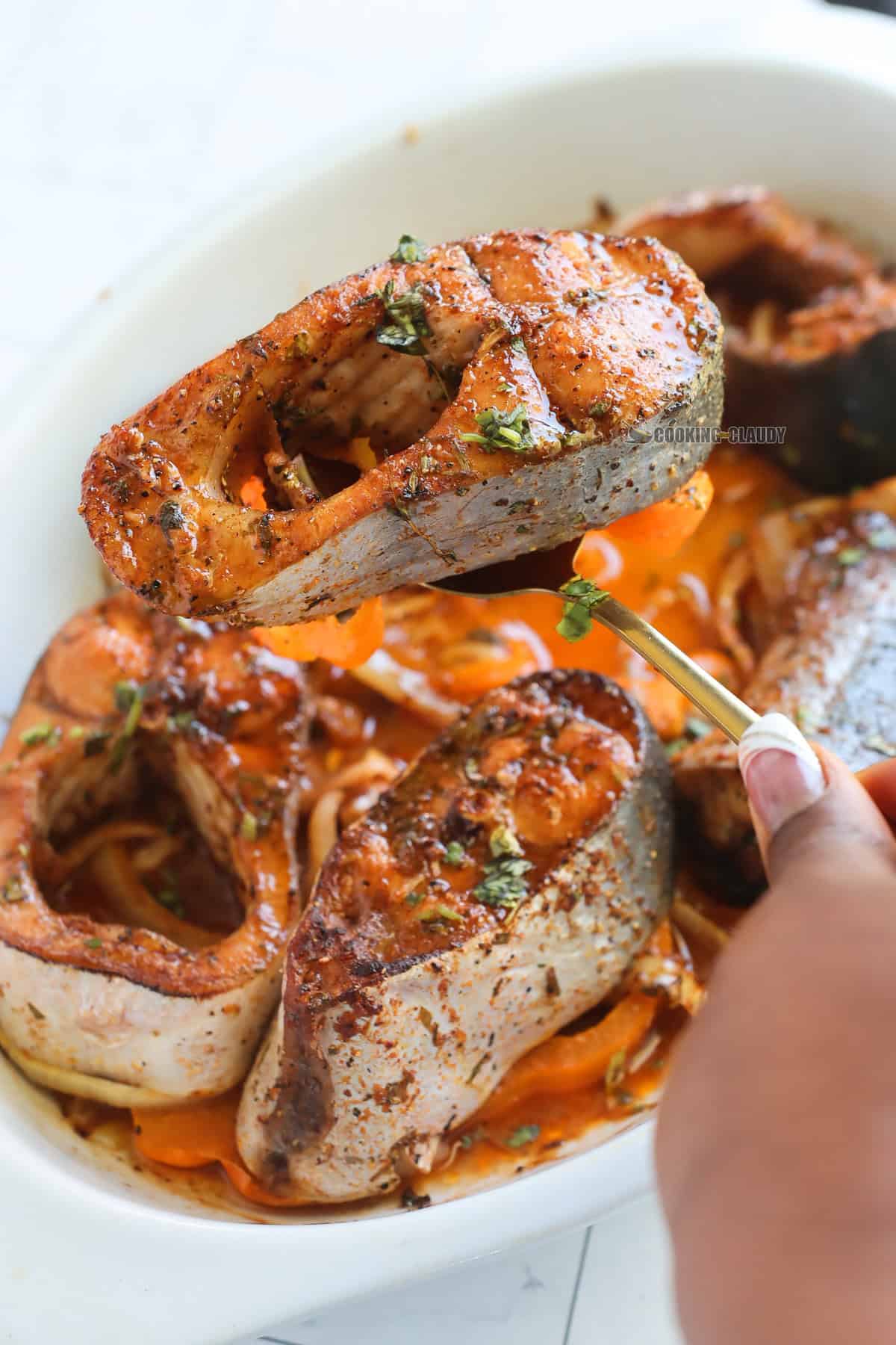 Person lifting a Baked Basa Fish with a spoon.