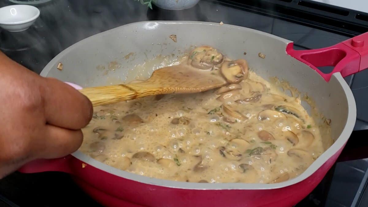 Wooden spoon stirring a pan of Creamy Mushroom Sauce.