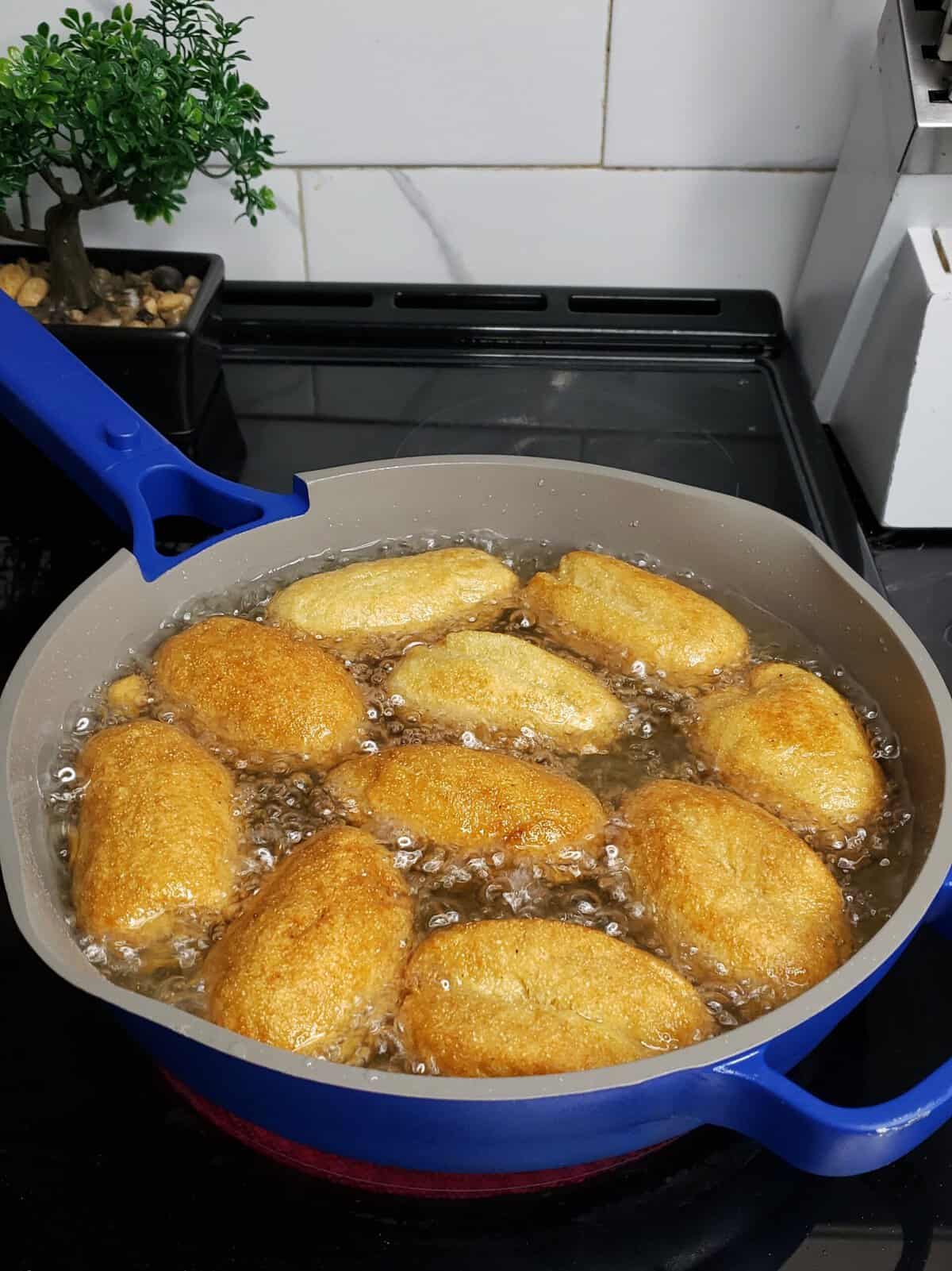 Rolls of dough frying in hot oil.