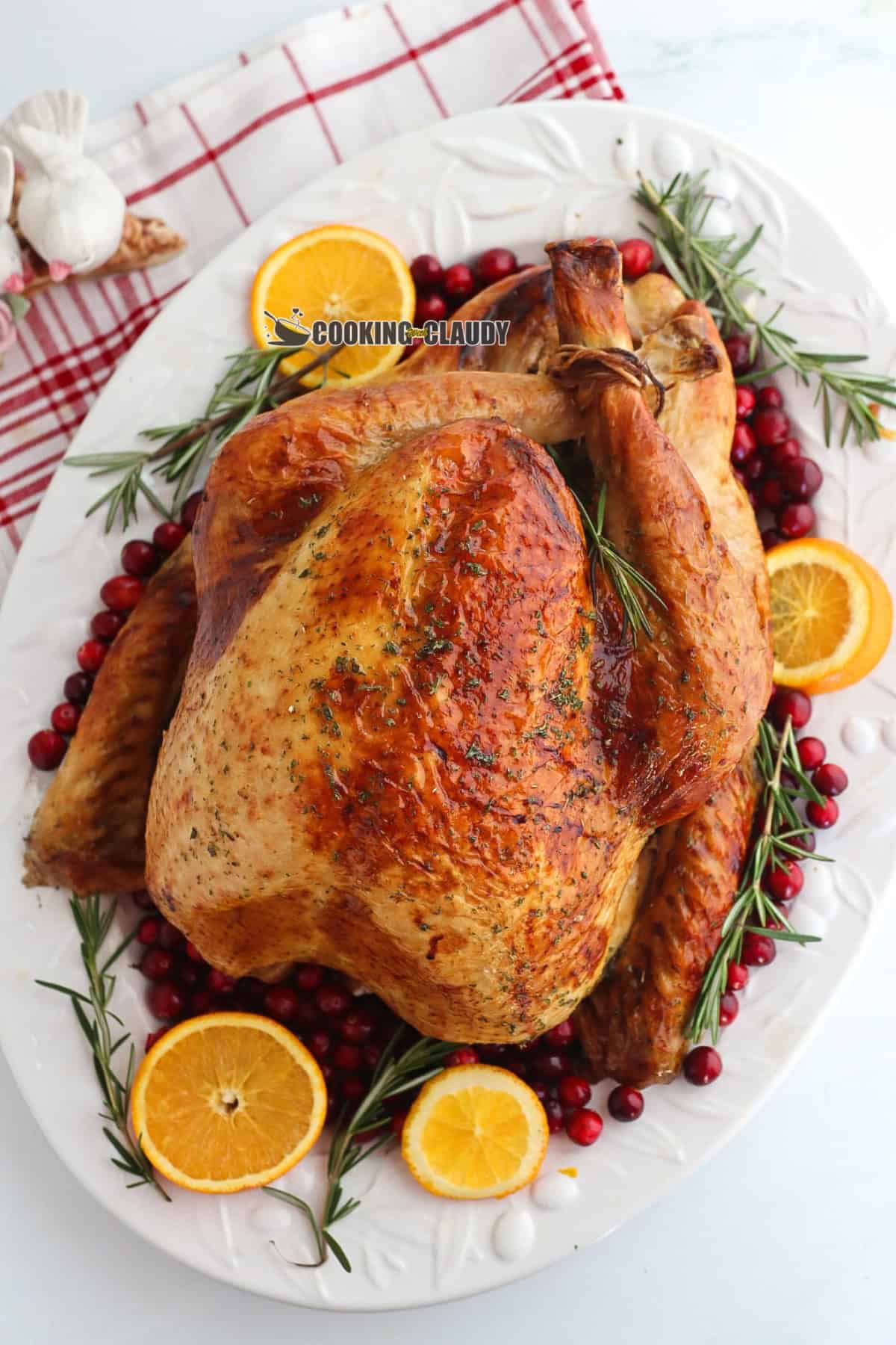 roasted turkey served on a plate with herbs and orange slices. 