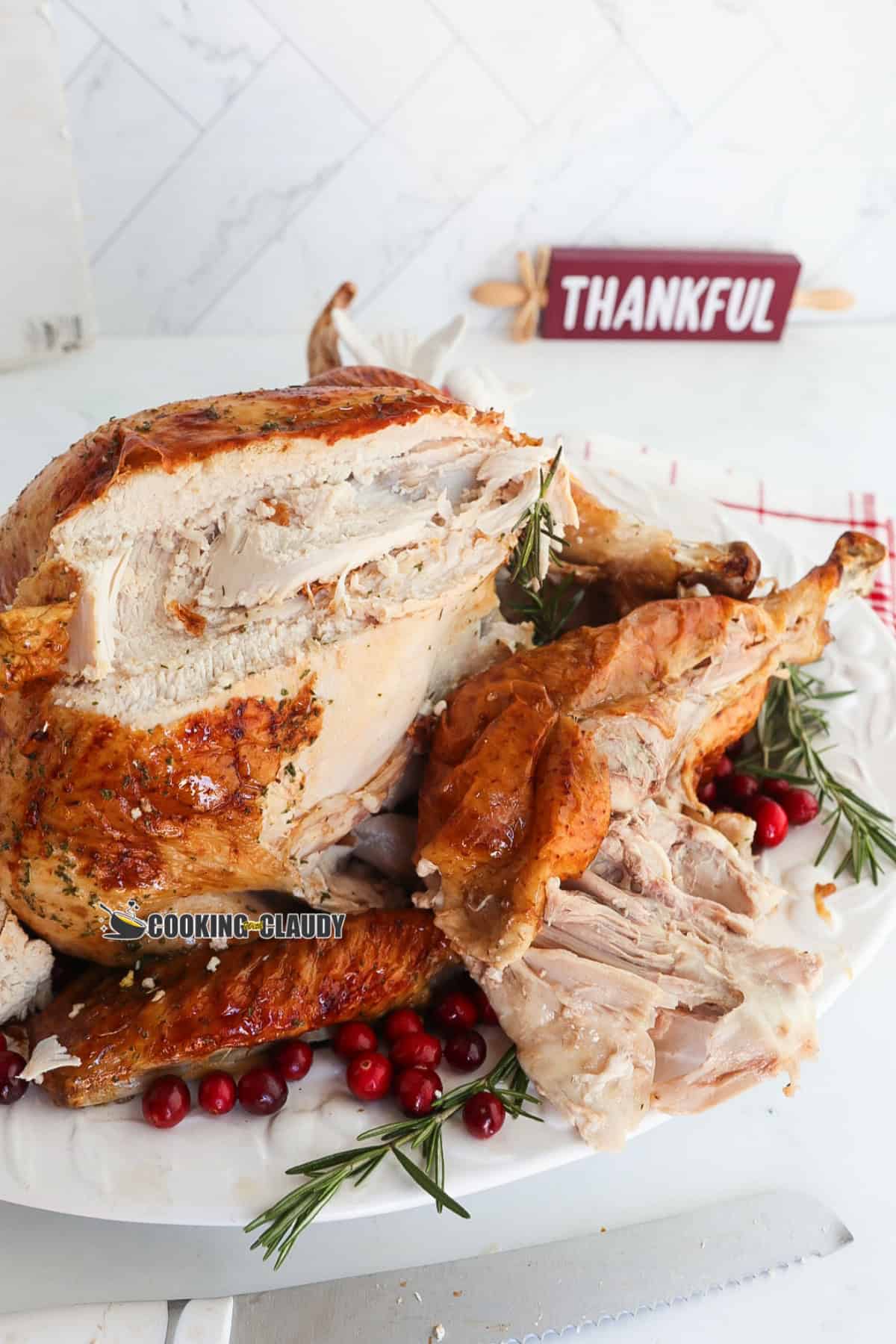 carved turkey meat in a plate with berries and rosemary. 