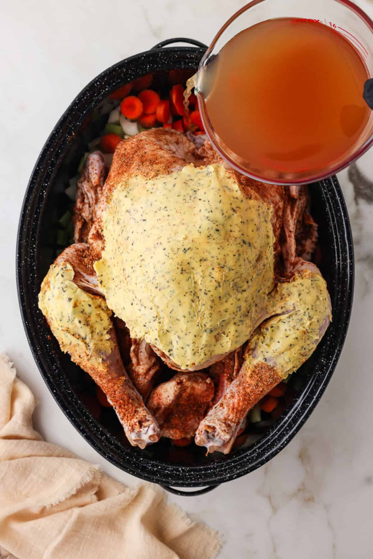 pouring stock into the pan with the prepared turkey. 