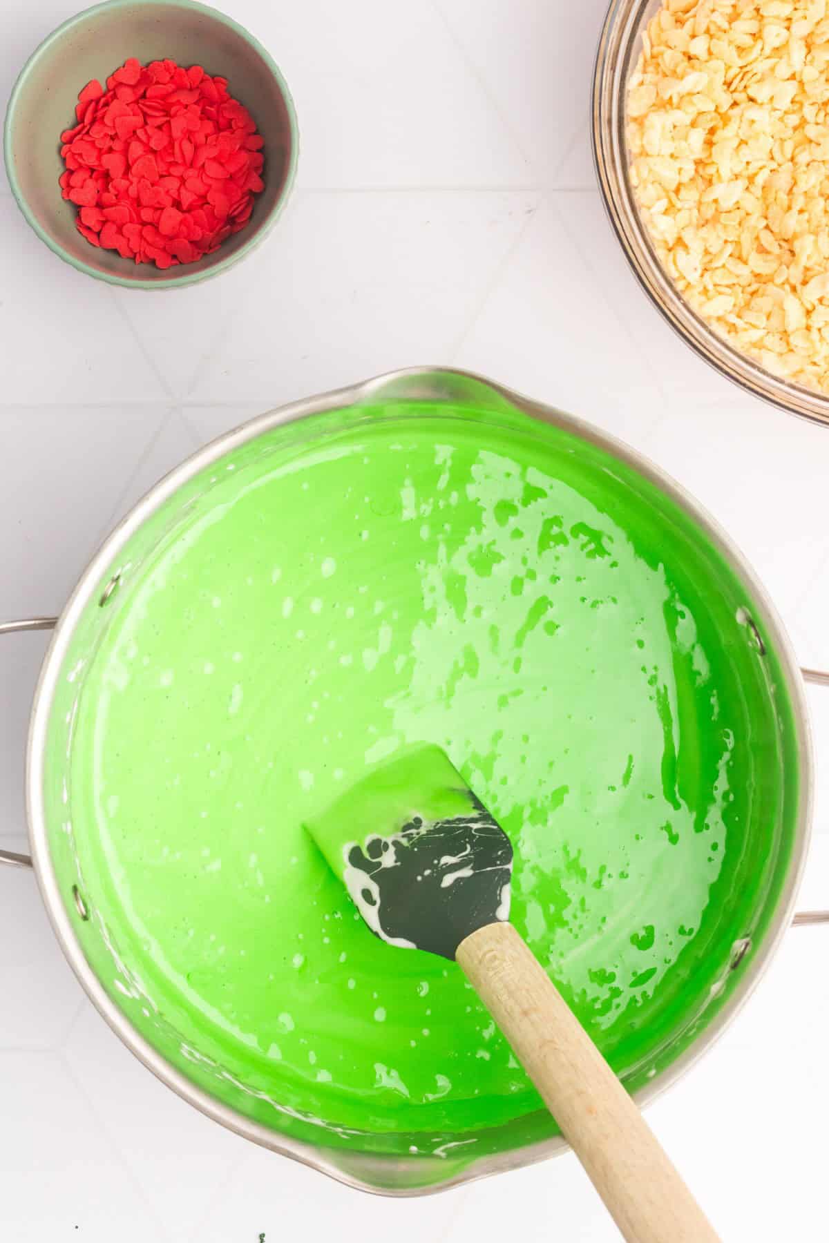 Bright green food color added to melted mini marshmallows in a large pot. 