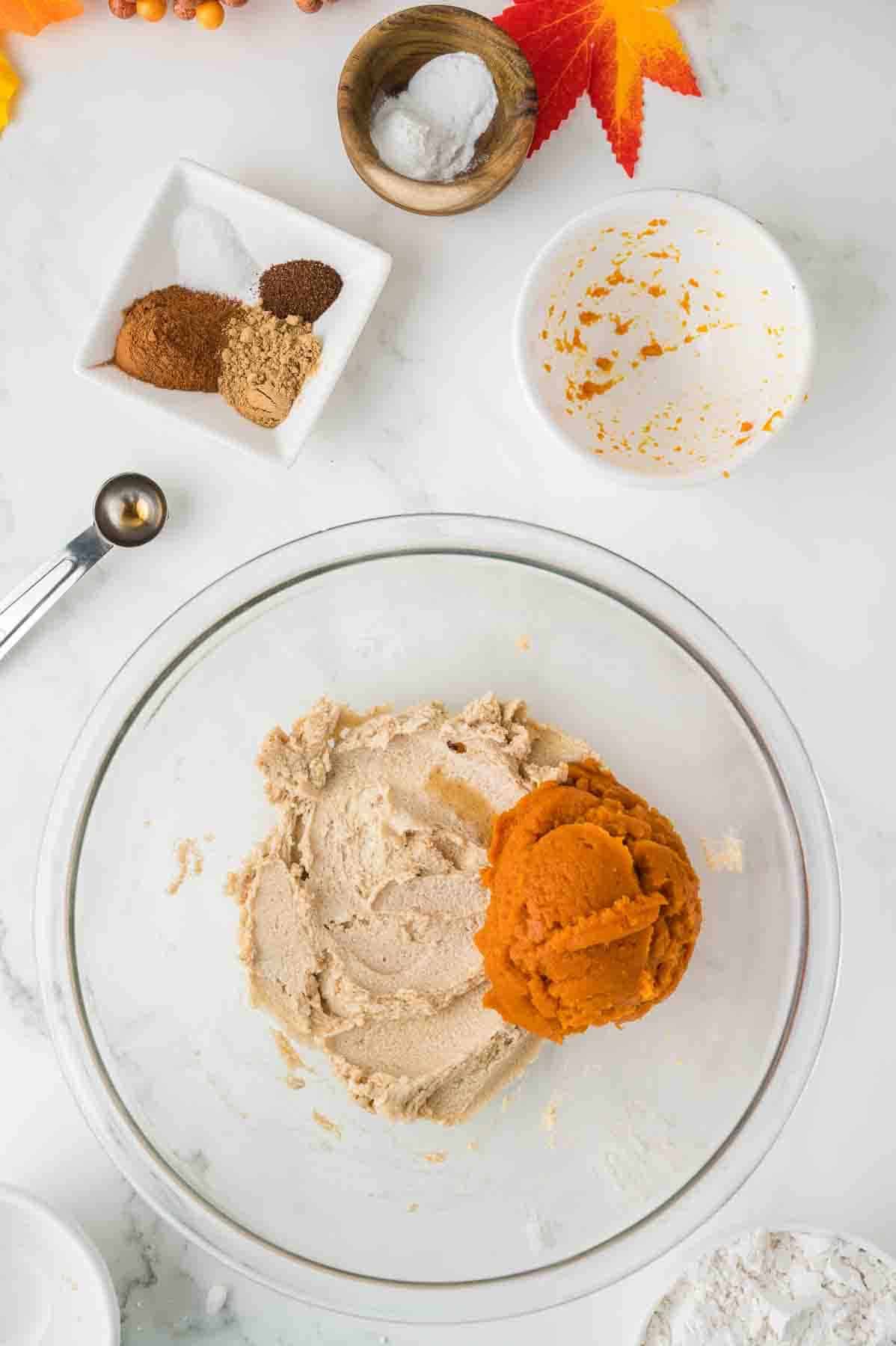 pumpkin puree added to creamed butter and sugar mixture in a bowl. 