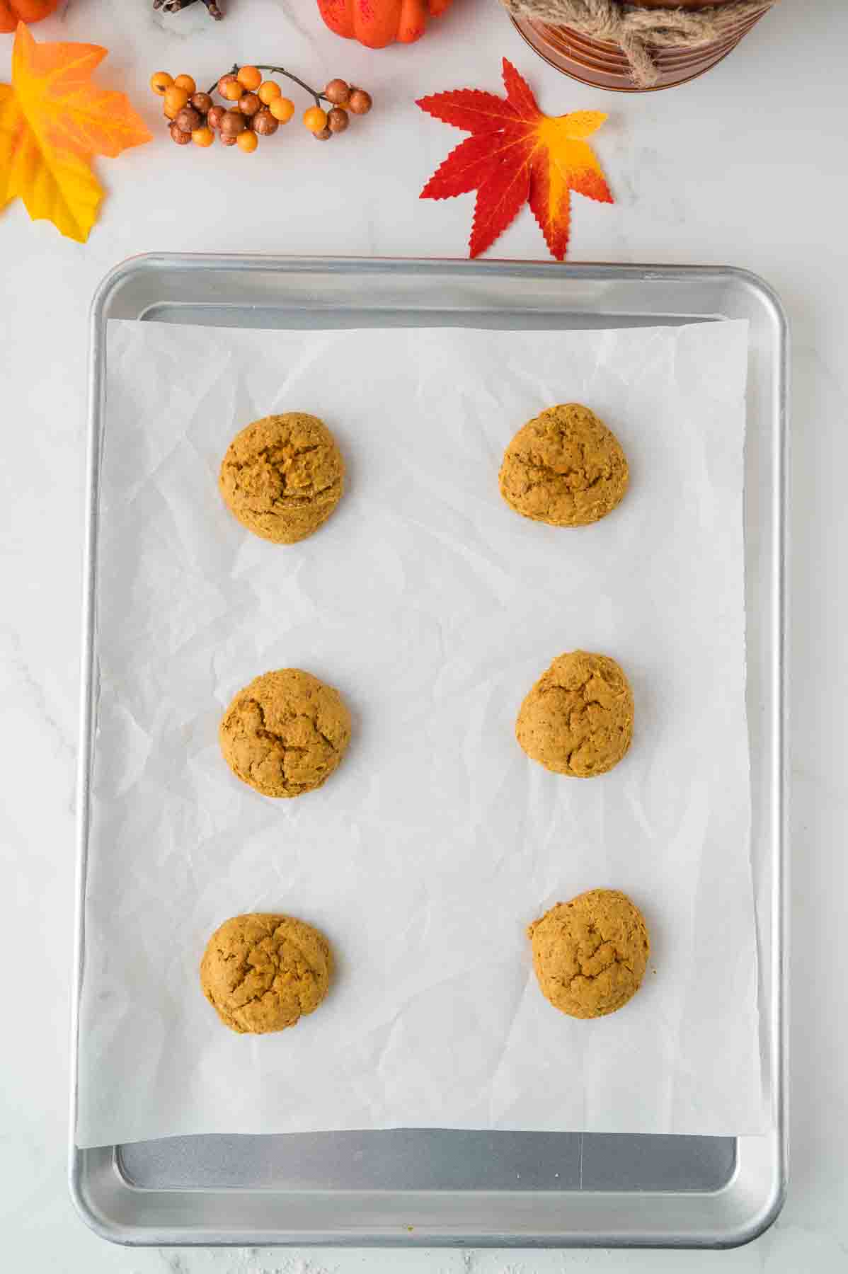 Cookie dough scooped on a baking sheet lined with parchment paper. 