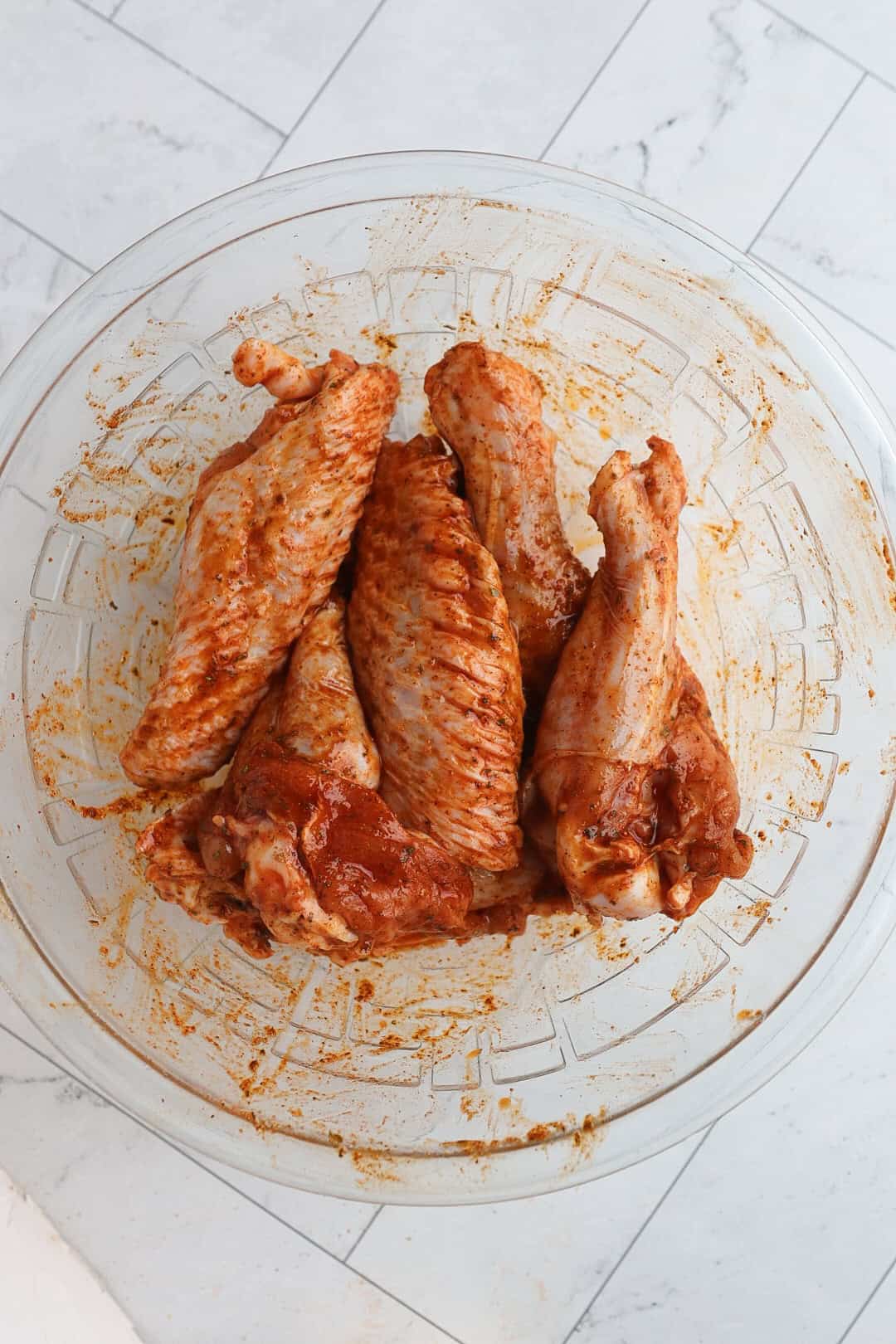 turkey wings in a small bowl, coated in a spicy marinade. 