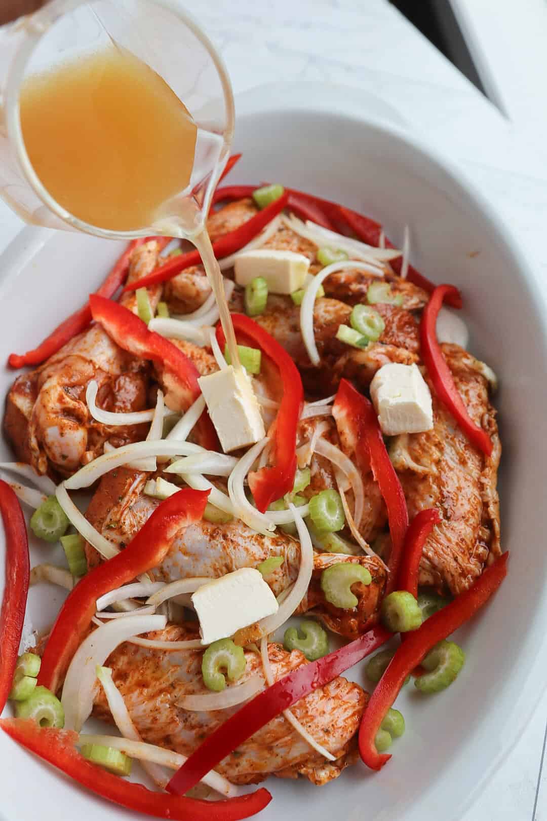 marinated turkey wings, vegetables and butter in a baking dish, topped with broth. 