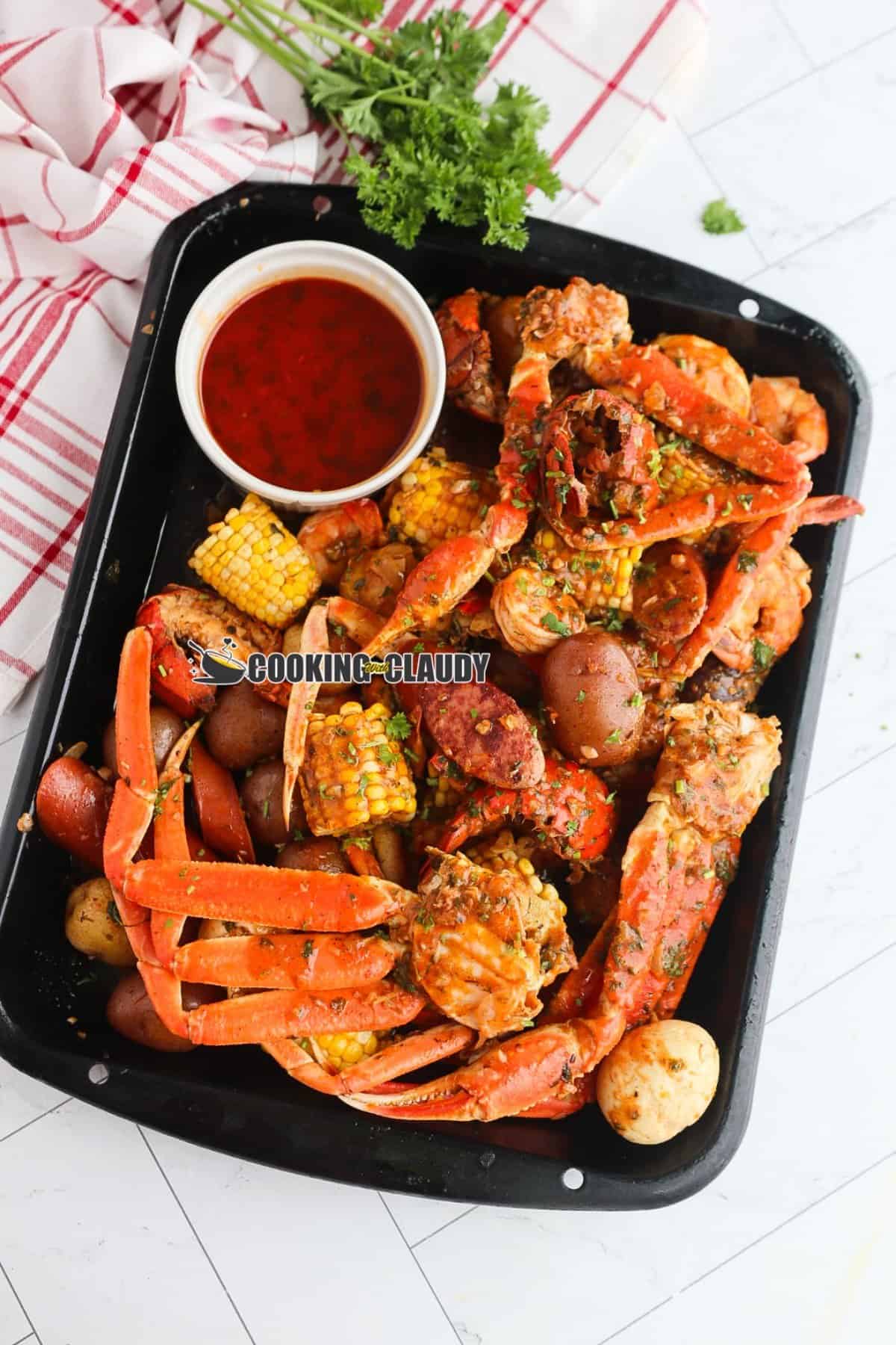 spicy and buttery seafood boil served on a platter with a butter dipping sauce. 