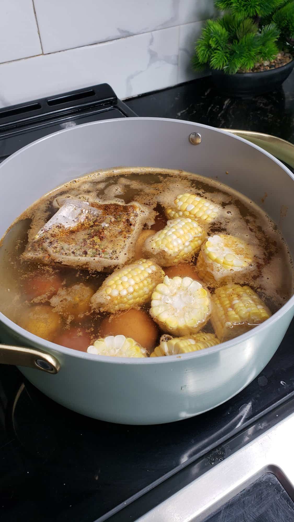 Cooking corn, potatoes and eggs in a pot. 