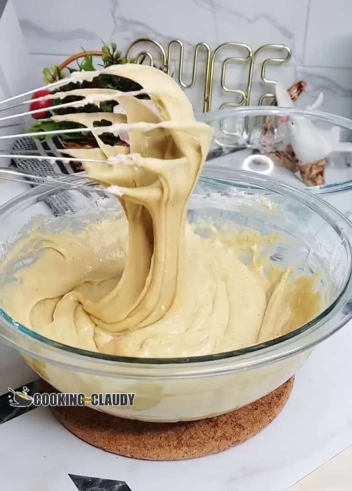 Whisk mixing batter for carrot cake loaf in a bowl, showing creamy texture