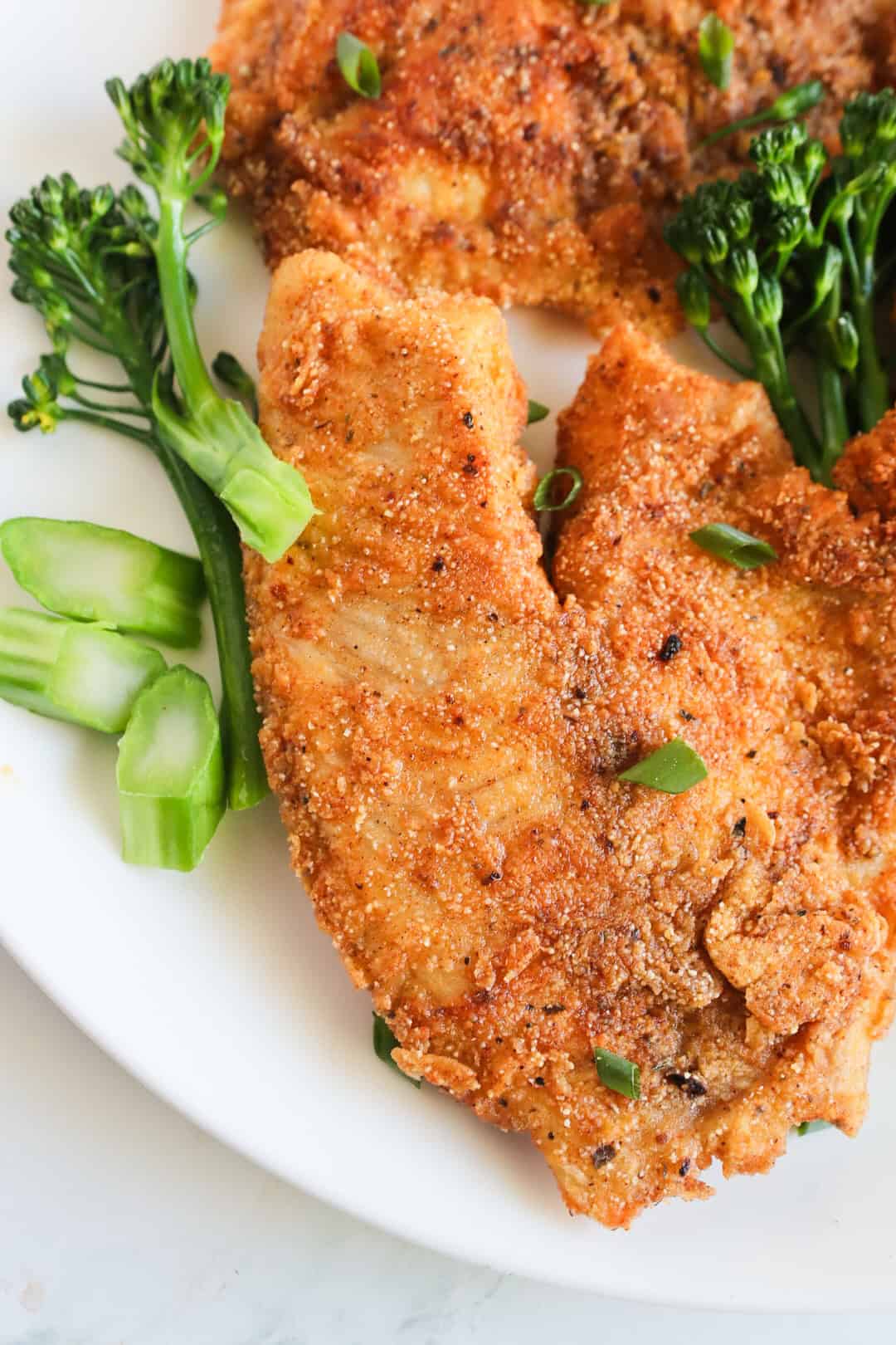 Crispy Pan Fried Fish and broccoli in a white plate