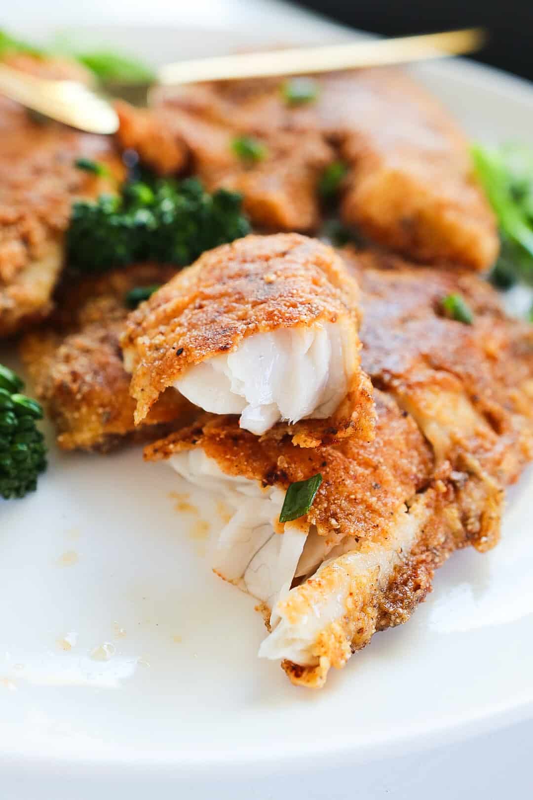 Crispy Pan Fried Fish and broccoli in a white plate