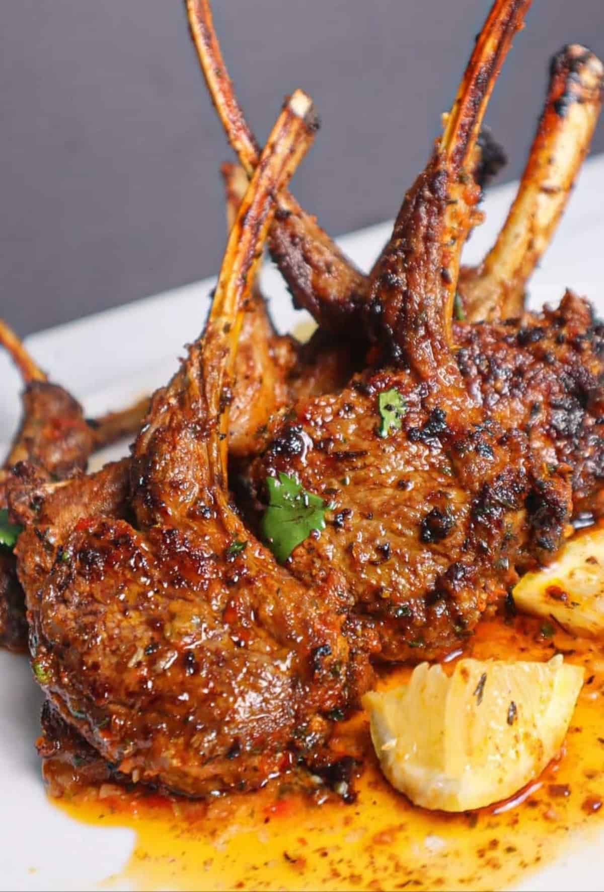 Baked Lamb Chops standing up on a white plate.