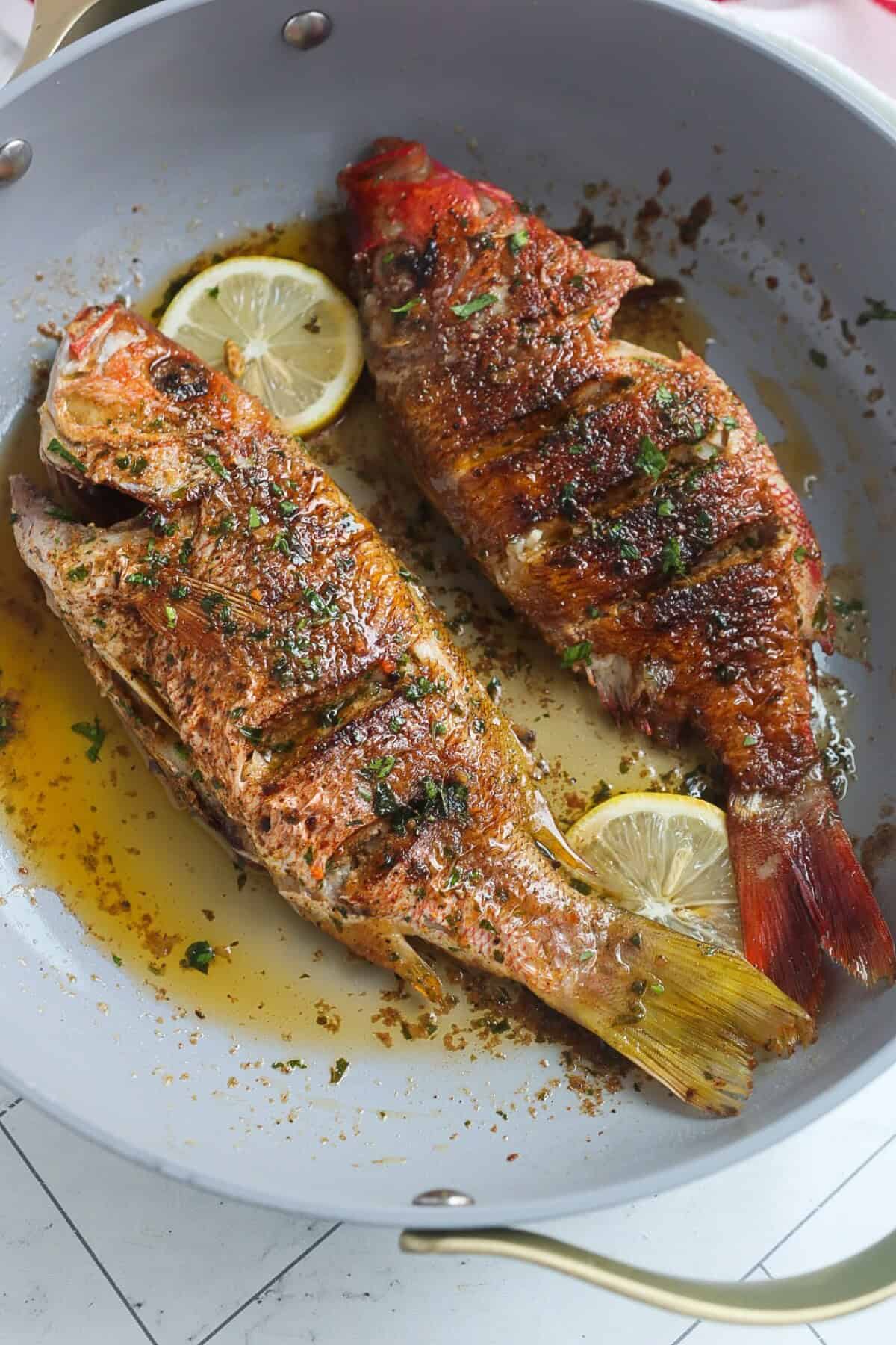 Crispy and flaky pan seared whole red snapper in a pan with lemon butter sauce.