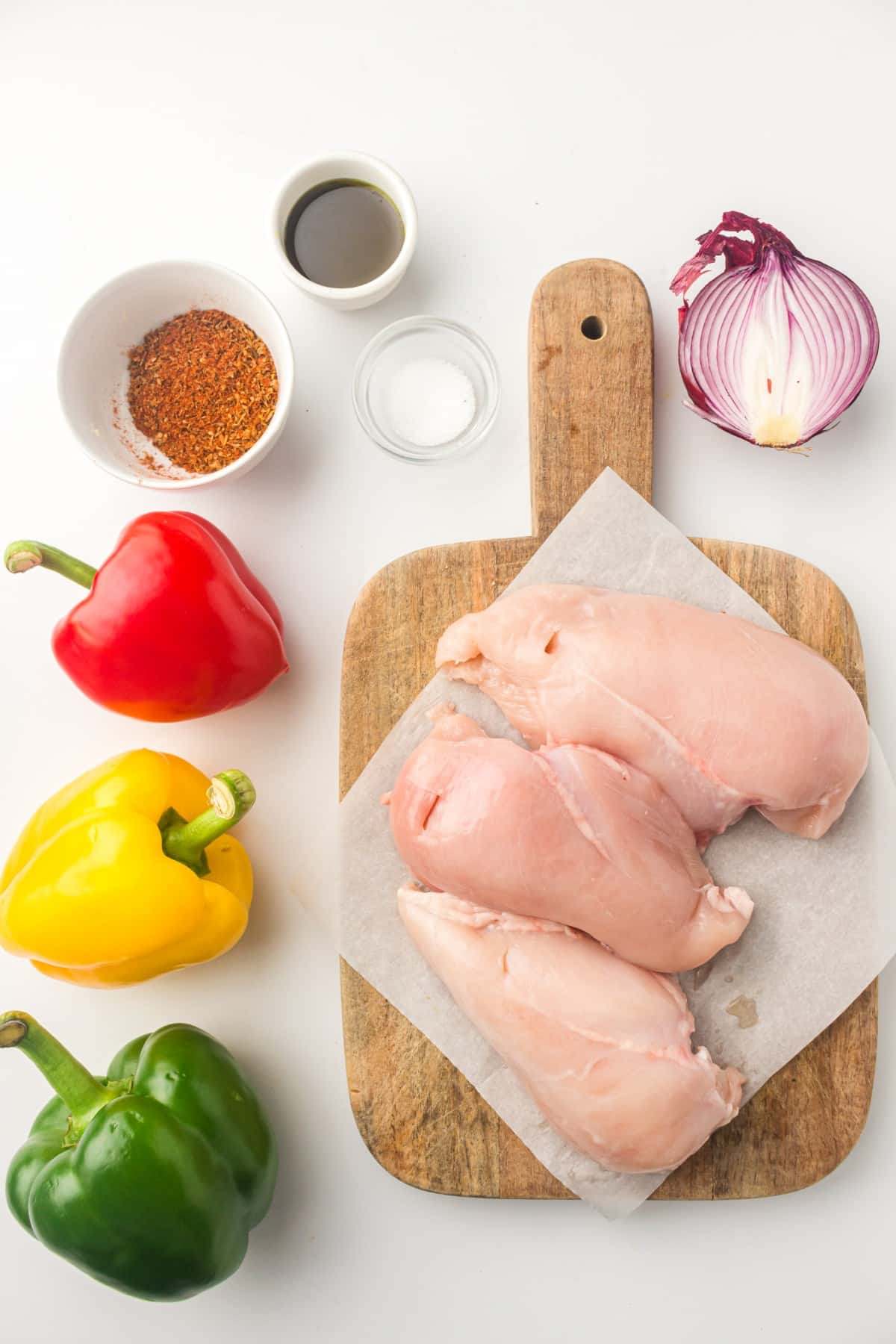 Ingredients for air fryer chicken fajitas: chicken breasts, bell peppers, red onion, fajita seasoning, and oil